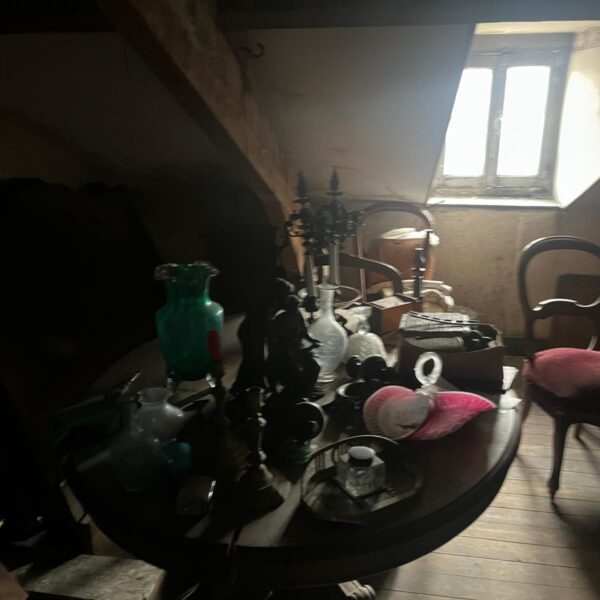 Objets anciens d’une succession rassemblés sur un guéridon dans un grenier à Boulogne-Billancourt